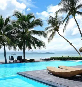 Beachfront pool with sun loungers under palms at The Blue Sky Resort Koh Payam