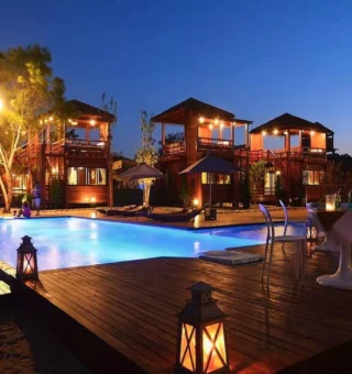 Pool and wooden villas at night at The Blue Sky Resort Koh Payam