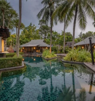 Tropical lagoon pool beside thatched pavilions at The Slate Phuket