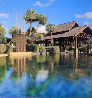Infinity pool reflecting palms and the main pavilion at The Slate Phuket