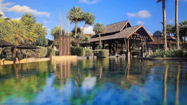 Infinity pool reflecting palms and the main pavilion at The Slate Phuket