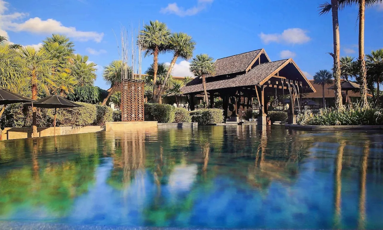 Infinity pool reflecting palms and the main pavilion at The Slate Phuket