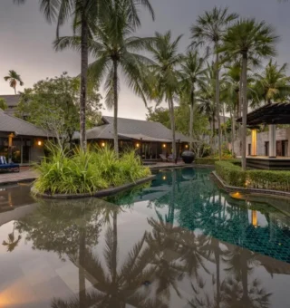 Lagoon pool at dusk lined with palms at The Slate Phuket